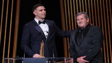 Two men in tuxedos stand side by side on stage