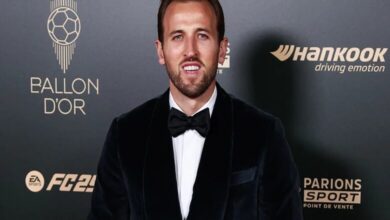 Harry Kane in a tuxedo poses confidently on a red carpet