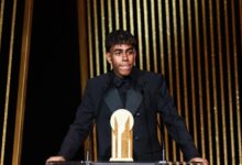 A man in a tuxedo stands confidently at a podium.