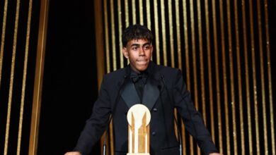 A man in a tuxedo stands confidently at a podium.