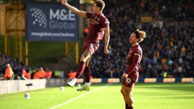 Two soccer players leap into the air on a vibrant green field.