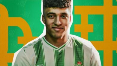 A male soccer player dressed in a green and white uniform prepares for action on the soccer field