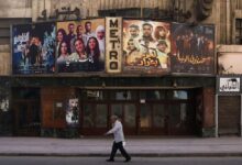 A man strolls by a movie poster in the bustling streets of Cairo.