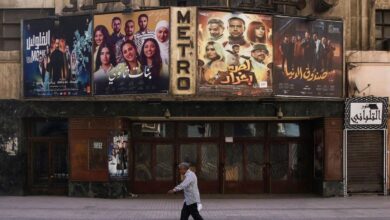 A man strolls by a movie poster in the bustling streets of Cairo.