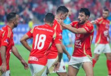 A group of men in red soccer uniforms joyfully celebrating their victory on the field.