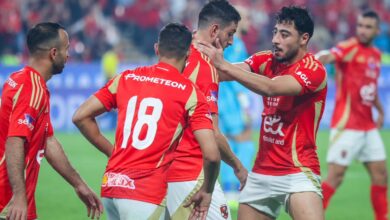 A group of men in red soccer uniforms joyfully celebrating their victory on the field.