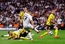 A soccer player dives to the ground, skillfully reaching for the ball to score a goal during an intense match.