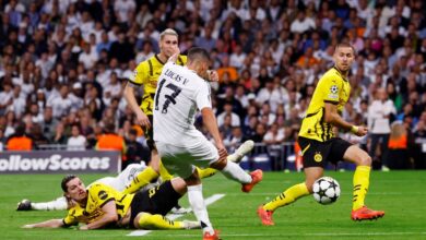 A soccer player dives to the ground, skillfully reaching for the ball to score a goal during an intense match.