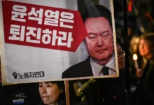 Protesters hold up signs with Yoon's picture during a protest outside parliament.