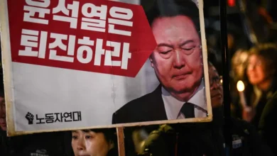 Protesters hold up signs with Yoon's picture during a protest outside parliament.